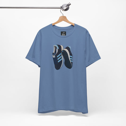 Oasis Blue t-shirt with graphic design of black and blue sneakers hanging on wooden hanger