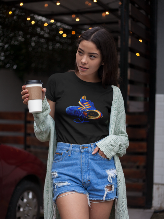 A woman wearing a black t-shirt with hand-illustrated blue and orange retro terrace trainer sneaker graphic print, On The Terrace casual clothing brand
