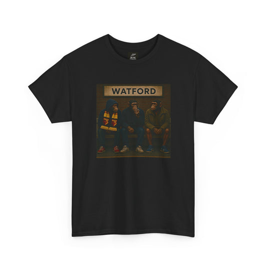 A black short-sleeve Watford t-shirt featuring a rectangular graphic print on the chest. The graphic shows three hooded figures sitting on a bench under a sign that reads 'WATFORD' in beige letters, with a dark background.