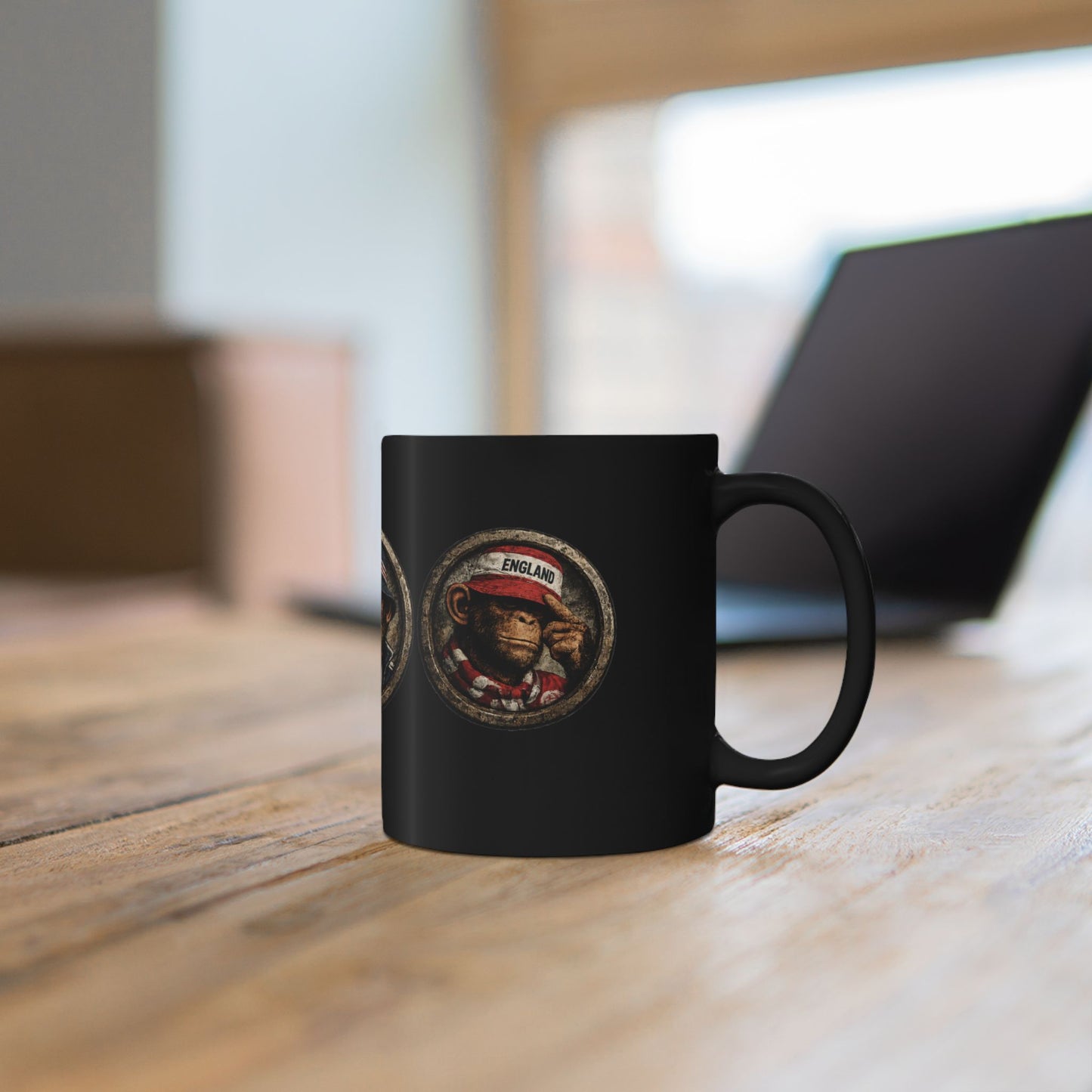 A black ceramic mug features three circular, stone-textured portrait emblems. The central emblem showcases a chimpanzee with a stern expression, wearing a navy blue casual jacket and a navy bucket hat with red and white stripes. The left emblem shows a monkey wearing an England St. George's cross bucket hat and a blue-and-white bar scarf. The right emblem shows a monkey in a red casual cap and scarf.
