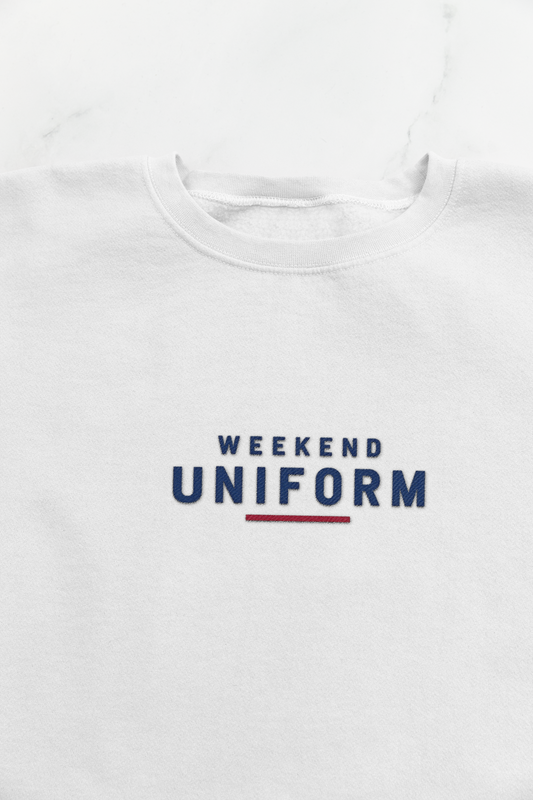 Close-up of the navy and red Weekend Uniform embroidery on the white sweatshirt