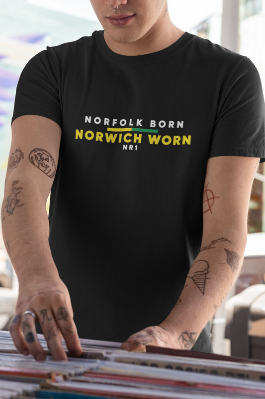 Tattooed man browsing records in a music shop wearing black Norfolk Born Norwich Worn tee