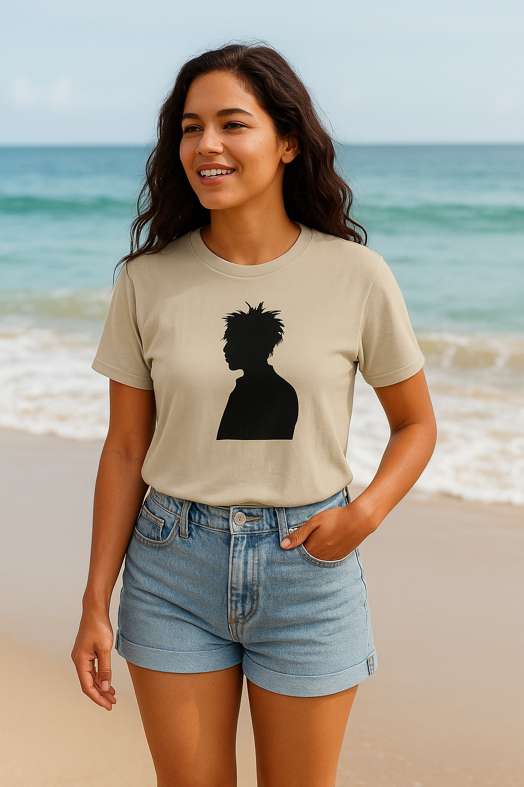 Smiling woman wearing beige t-shirt with black silhouette graphic and denim shorts at the beach