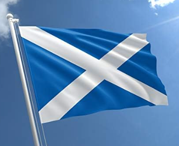 Scottish flag with white diagonal cross on blue background waving against clear sky