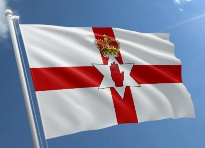 Flag of Northern Ireland with red cross, white background, red hand emblem, and crown against blue sky