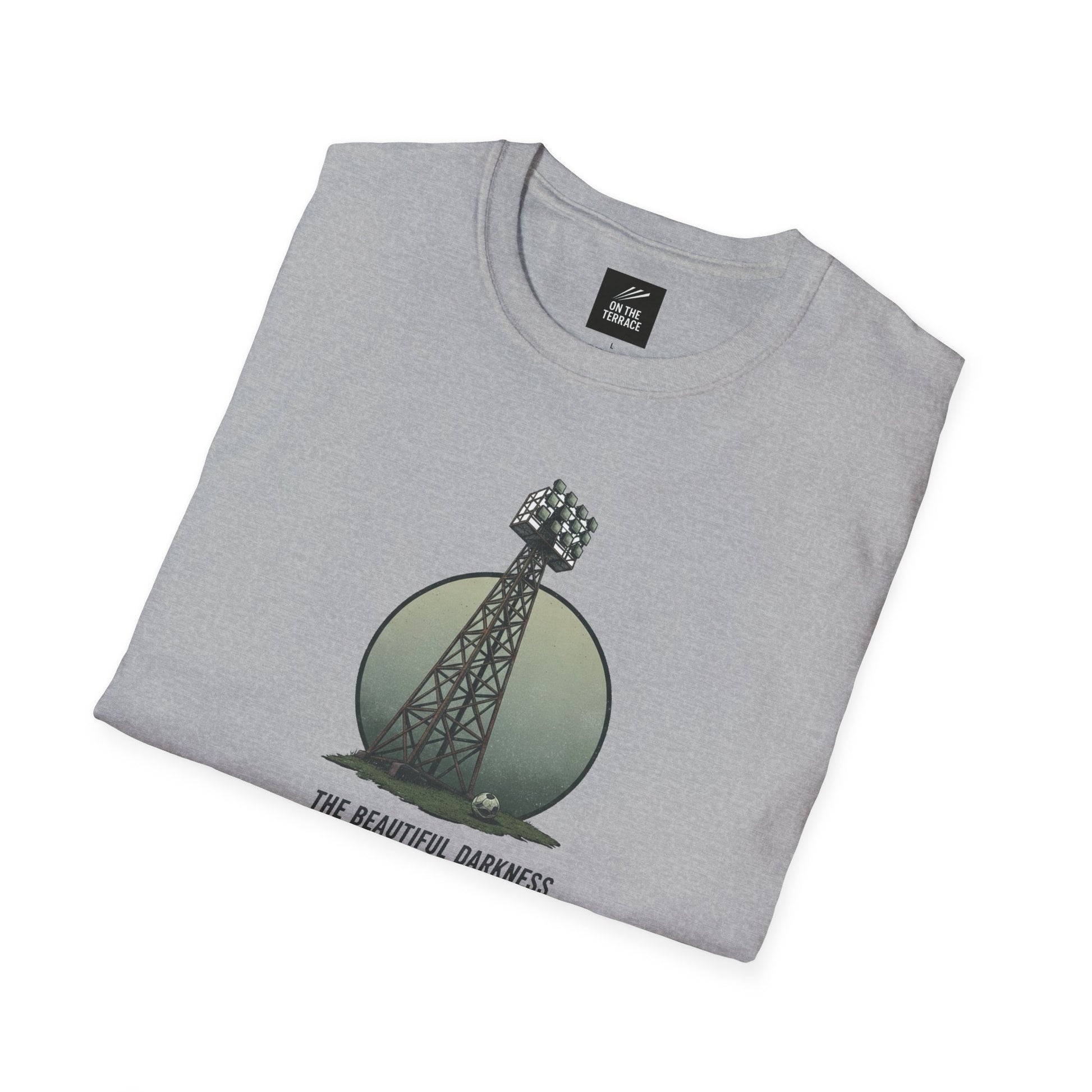 Light gray folded t-shirt with a stadium floodlight tower and football design, text 'The Beautiful Darkness'
