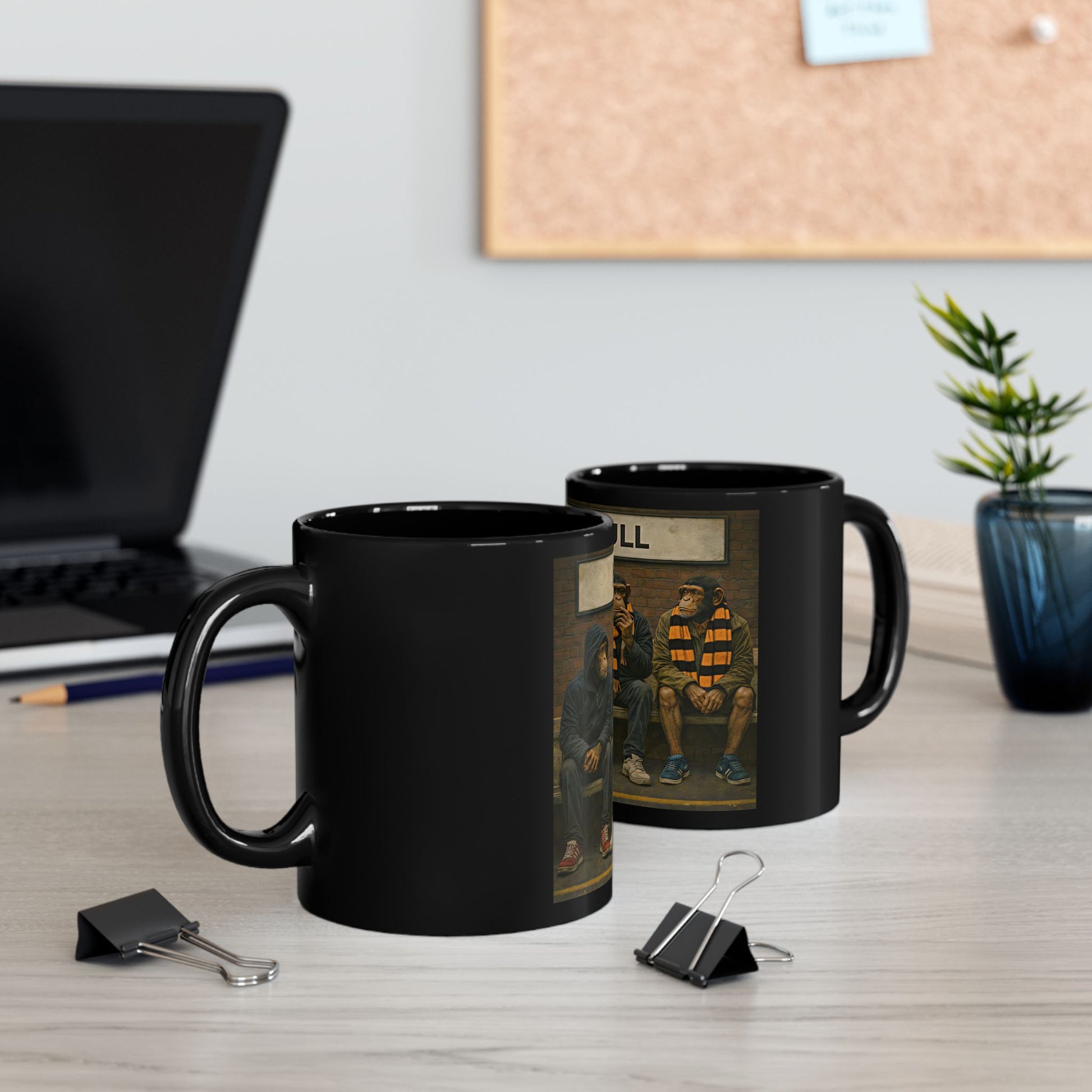 Two black mugs with printed designs on a desk with office supplies and a plant.