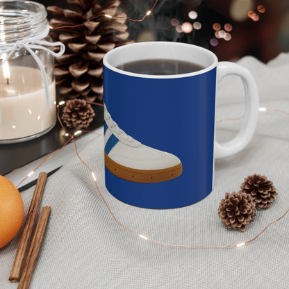Steaming coffee mug with blue sneaker design, surrounded by pinecones, cinnamon sticks, orange, candle, and string lights on fabric