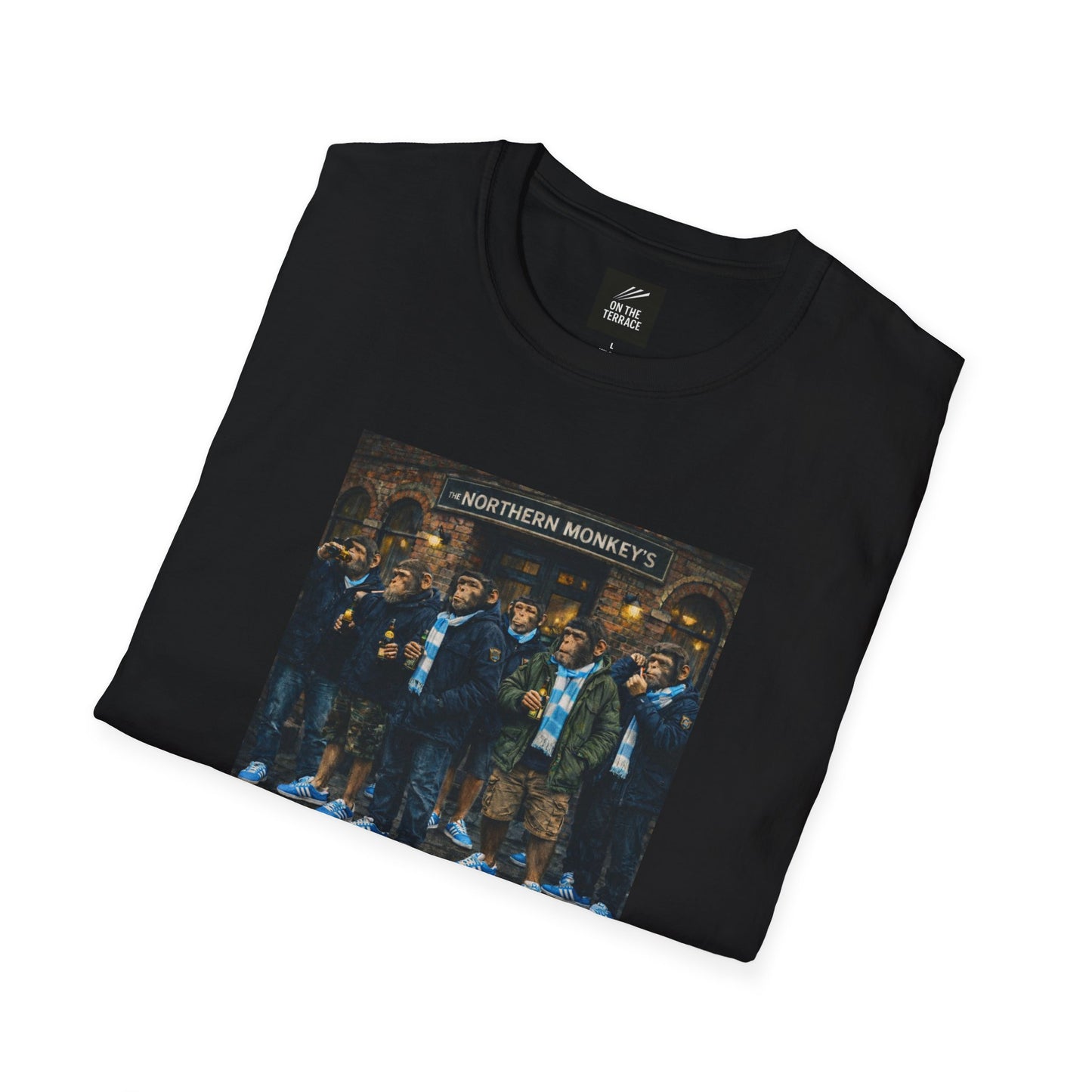 Black folded t-shirt with a graphic of chimpanzees dressed as Manchester City fans in scarves and parkas standing outside a pub called "The Northern Monkey's."