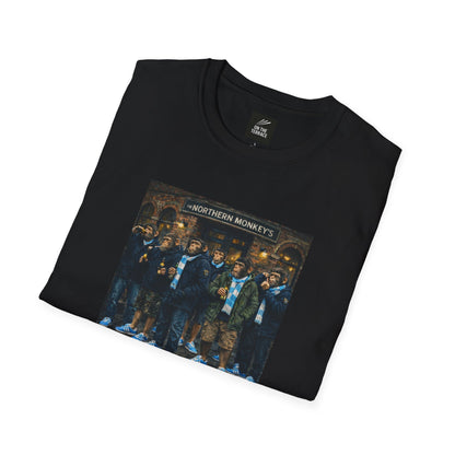 Black folded t-shirt with a graphic of chimpanzees dressed as Manchester City fans in scarves and parkas standing outside a pub called "The Northern Monkey's."