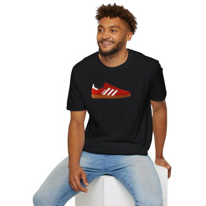 Smiling man wearing black t-shirt with red sneaker graphic and light blue jeans, sitting on white block