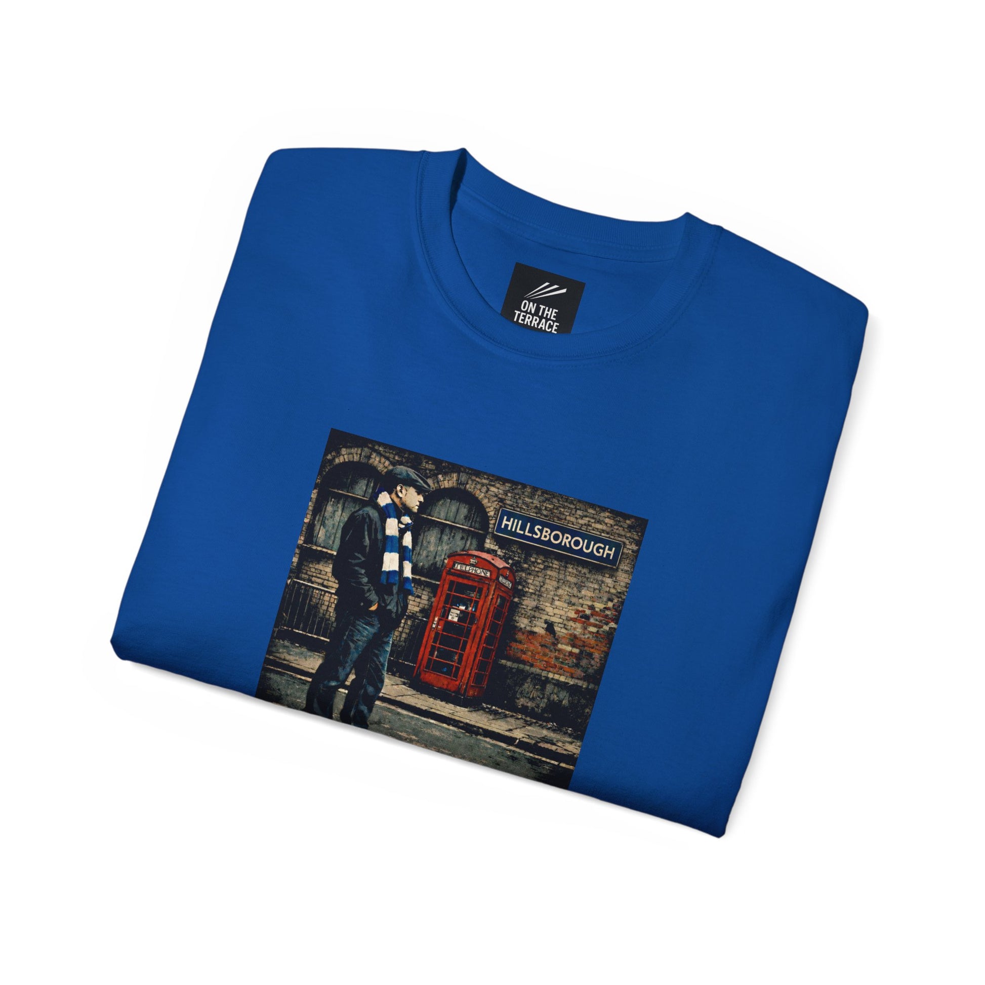 Folded blue t-shirt with a graphic of a person by a red telephone box and 'Hillsborough' sign.