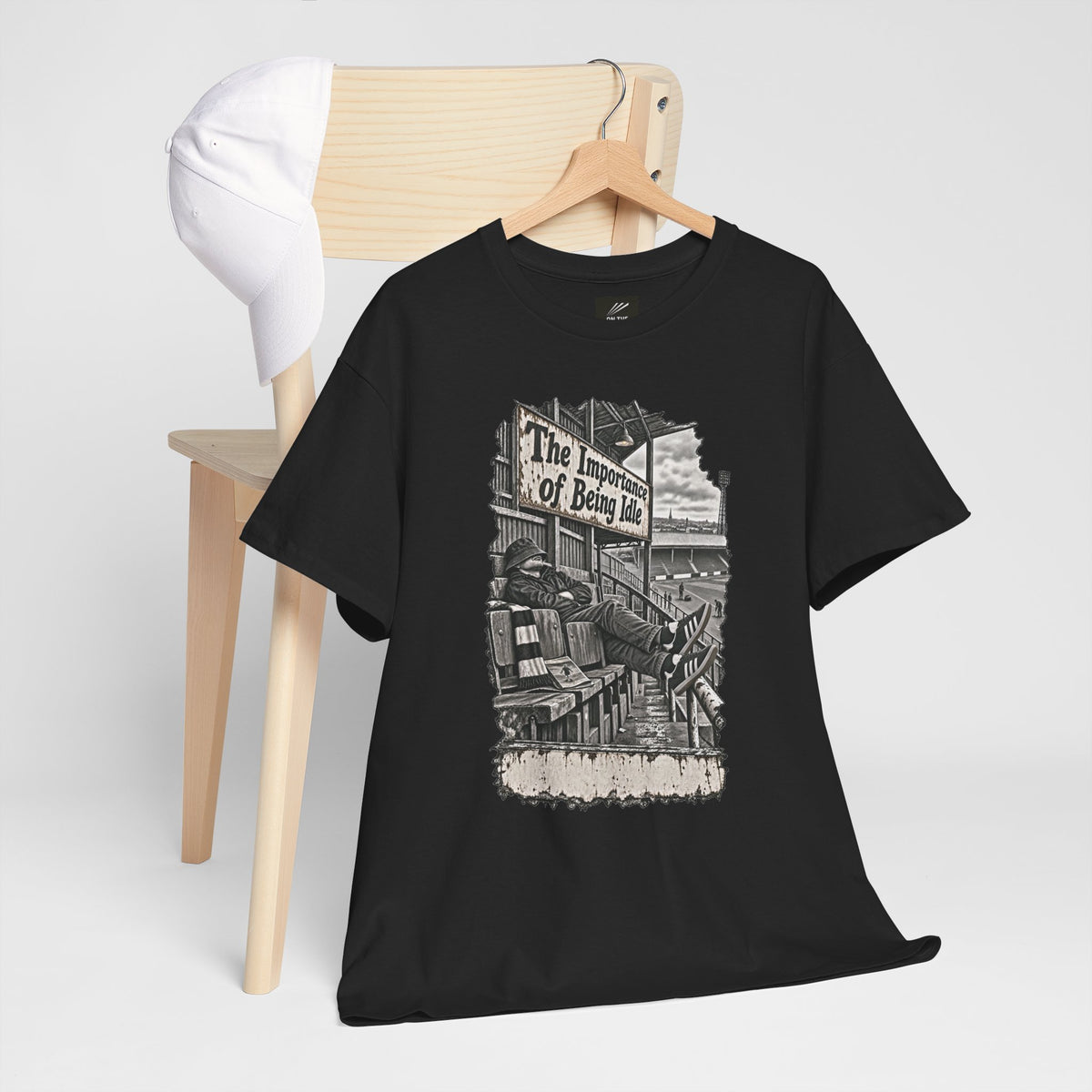 Black Oasis Importance of Being Idle T-shirt on a hanger over a wooden chair