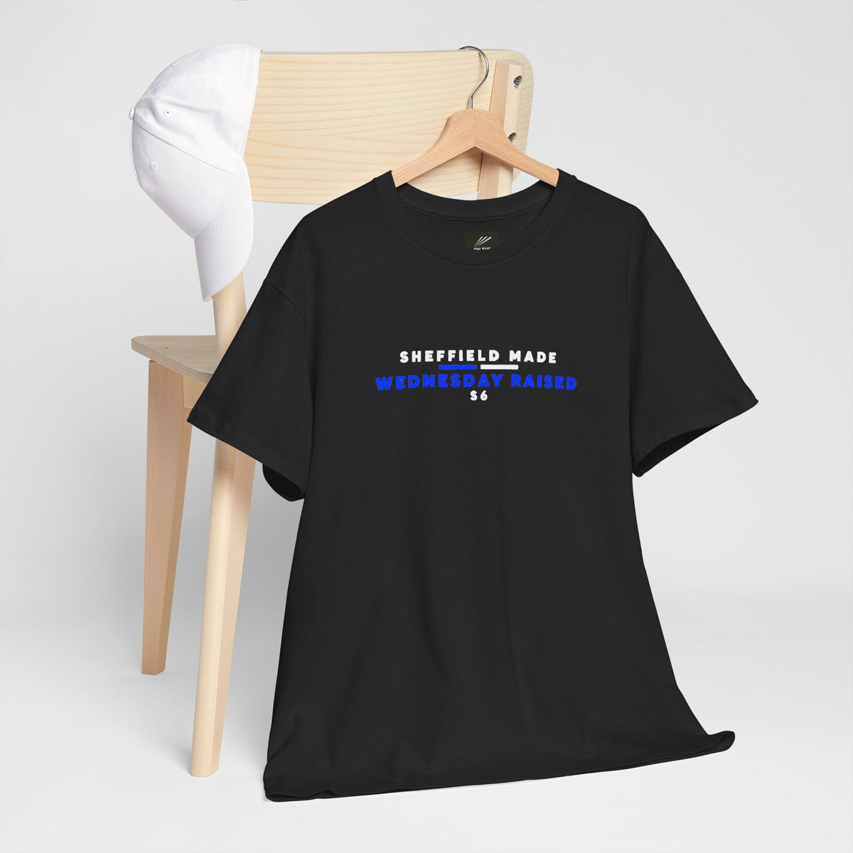 Black Sheffield Made Wednesday Raised T-shirt on a hanger over a wooden chair