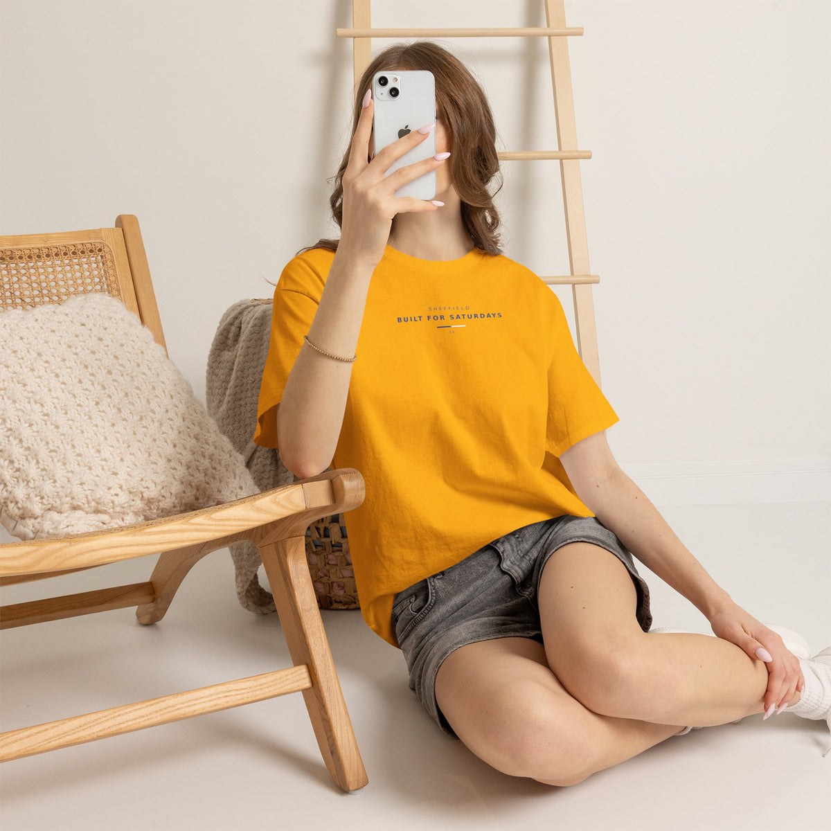 Woman sitting on the floor taking a mirror selfie in the gold Sheffield Wednesday slogan tee