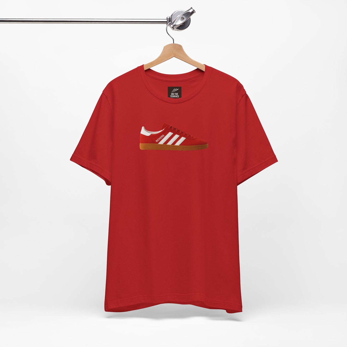 Red t-shirt with printed image of red sneaker with white stripes and gum sole hanging on metal hanger