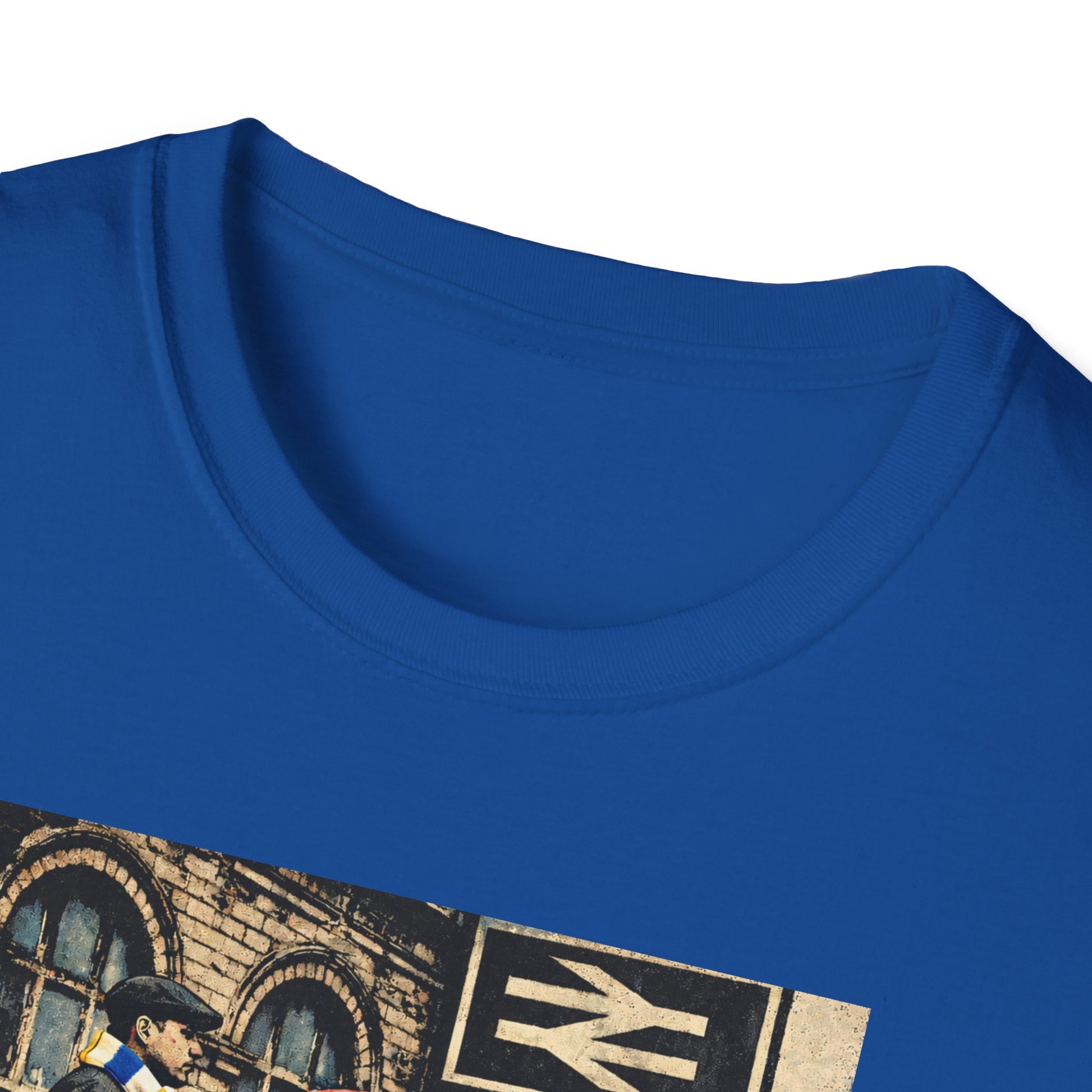 A close-up view of the upper front of a royal blue T-shirt against a white background. The ribbed crew neckline and stitching are clearly visible. The top edge of a printed image appears below the collar, showing part of a brick building, a black-and-white railway symbol, and the partial word “LEEDS.” The focus is on the fabric texture and collar detail.