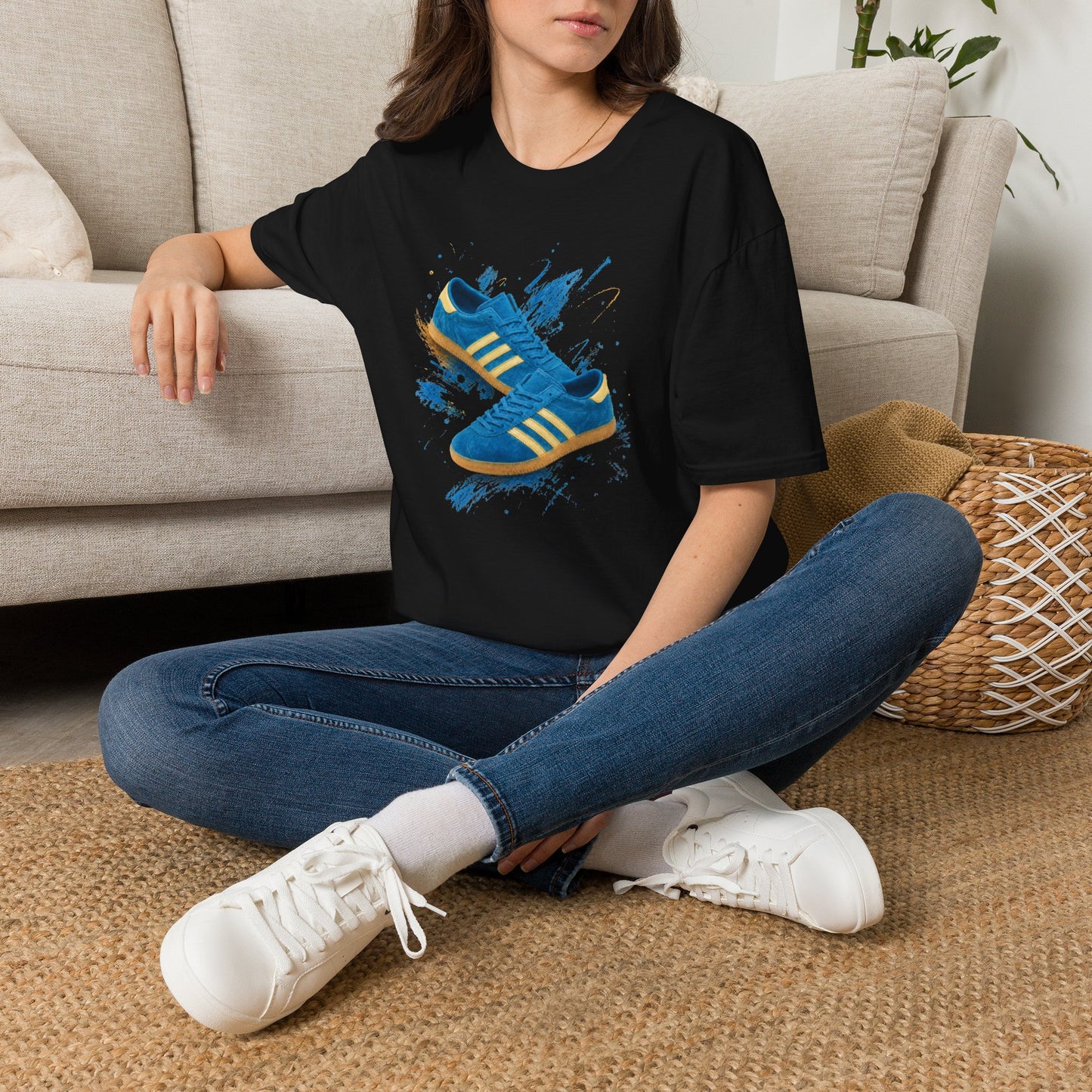 Person wearing a black t-shirt with a graphic design and text, sitting on the floor in a living room.