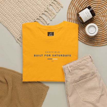 Gold Sheffield Built For Saturdays tee flat lay with knitwear, cord trousers and candle