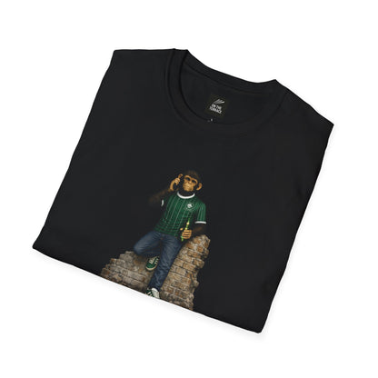 A folded black t-shirt featuring a chimpanzee wearing a green and white pinstriped football jersey and green trainers, leaning on a brick wall while using a mobile phone.