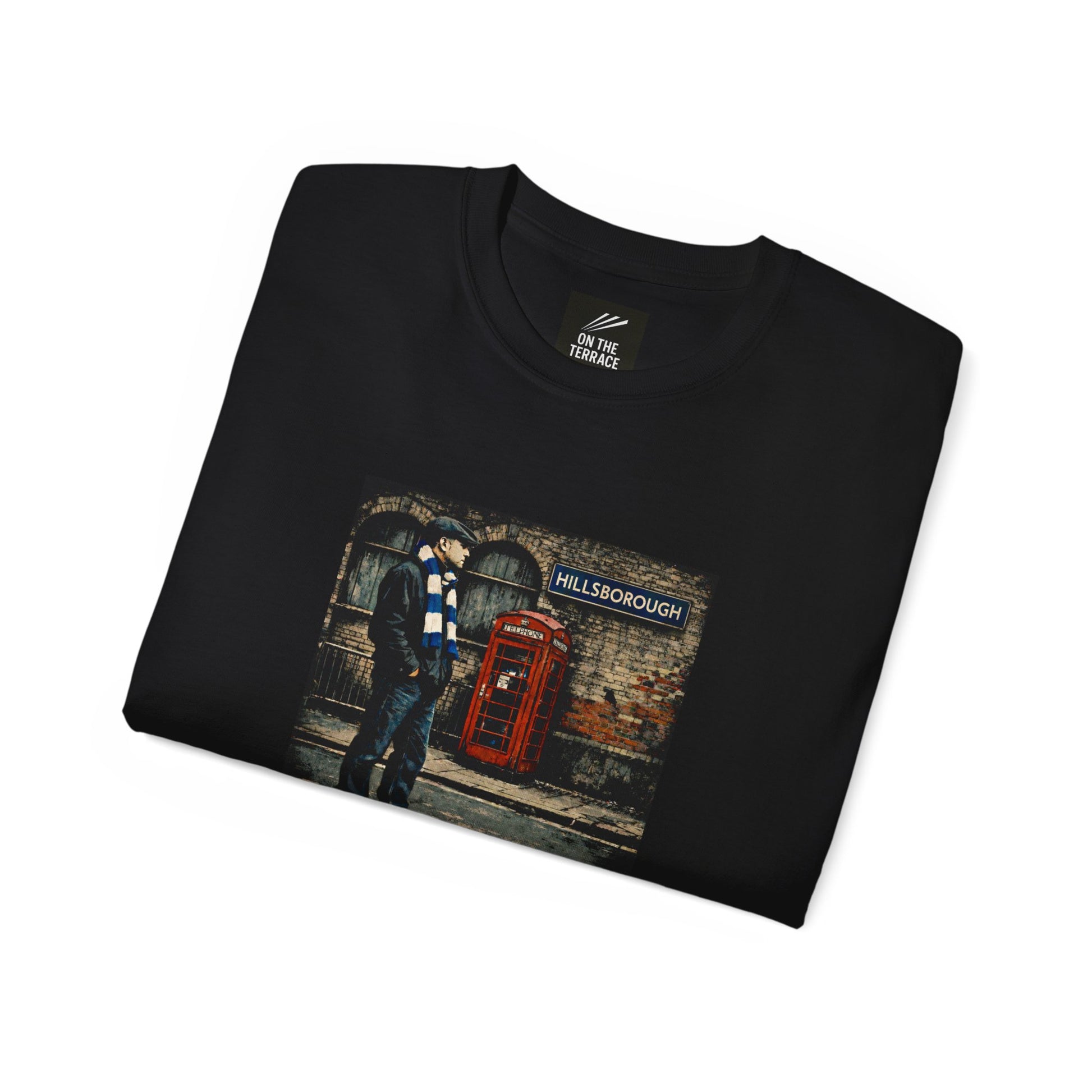 Folded black t-shirt with a graphic of a person at a red telephone box and 'Hillsborough' sign.