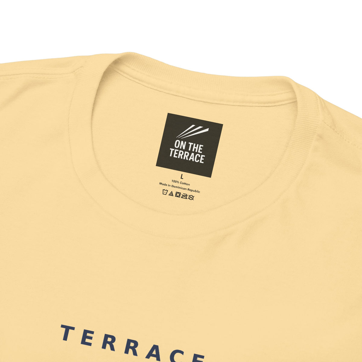 Close-up of the On The Terrace neck label and Terrace Code print on the pale yellow tee