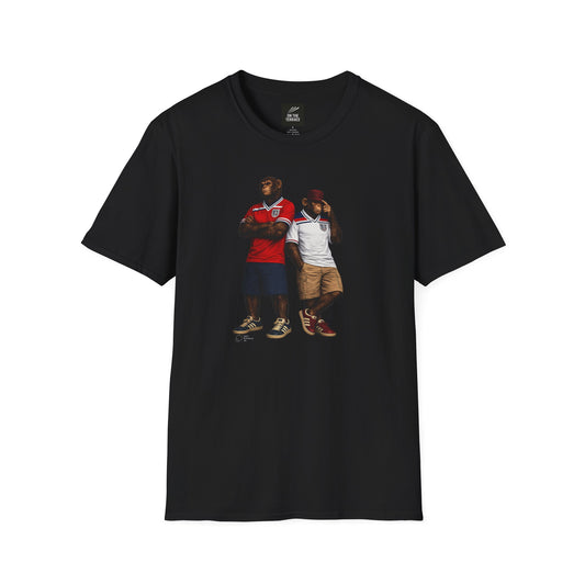 A black short-sleeved t-shirt featuring a central graphic of two chimpanzees dressed as England national football team supporters. The chimpanzee on the left stands with arms crossed, wearing the iconic 1982 World Cup red away jersey with blue and white shoulder stripes. The chimpanzee on the right wears the matching 1982 white home jersey, khaki cargo shorts, and a red bucket hat, gesturing toward his head