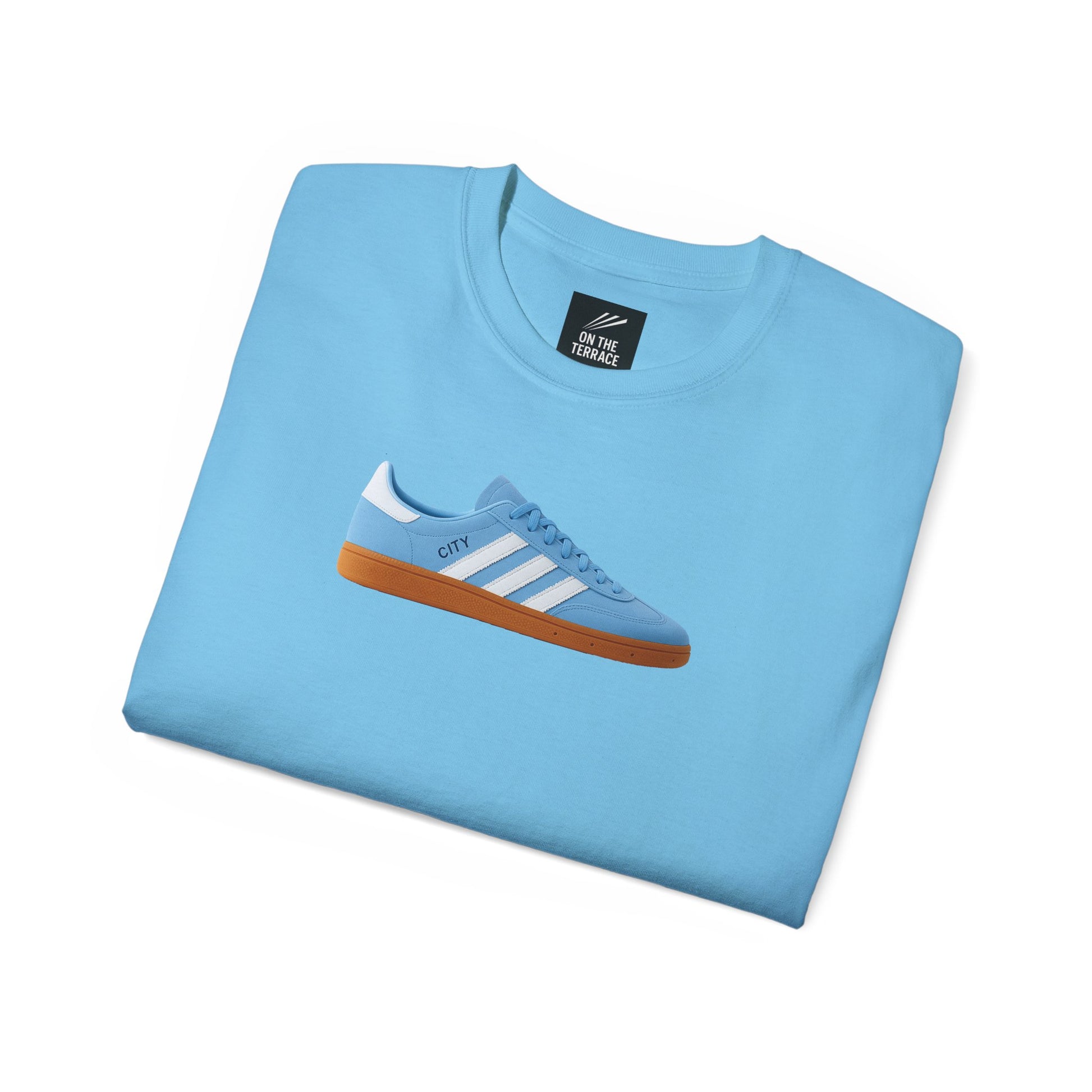 Light blue crewneck t-shirt with a graphic of a blue sneaker with white stripes and gum sole, folded flat