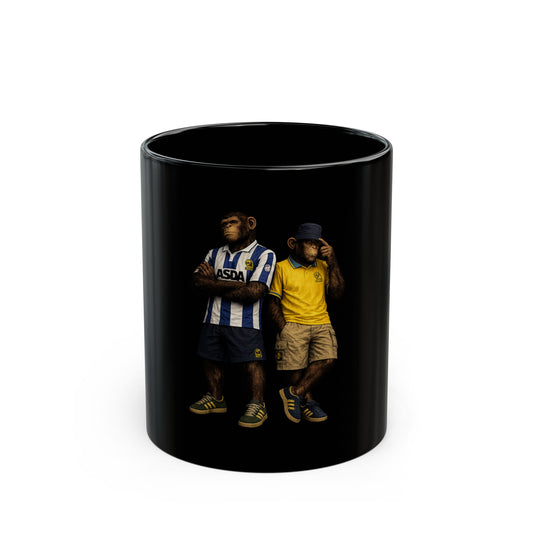 A black ceramic coffee mug featuring a detailed graphic print, showing two chimpanzees dressed in retro Sheffield Wednesday football kits; one wears the blue-and-white striped ASDA home shirt, and the other wears a yellow away shirt with a navy bucket hat.