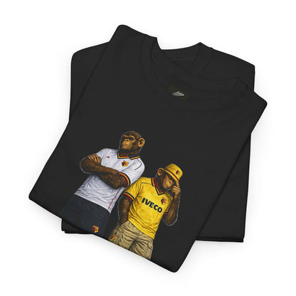 A folded black Watford t-shirt featuring a graphic print of two chimpanzees dressed in football jerseys, one in a white AS Roma jersey and the other in a yellow IVECO jersey, displayed on a clean white background.