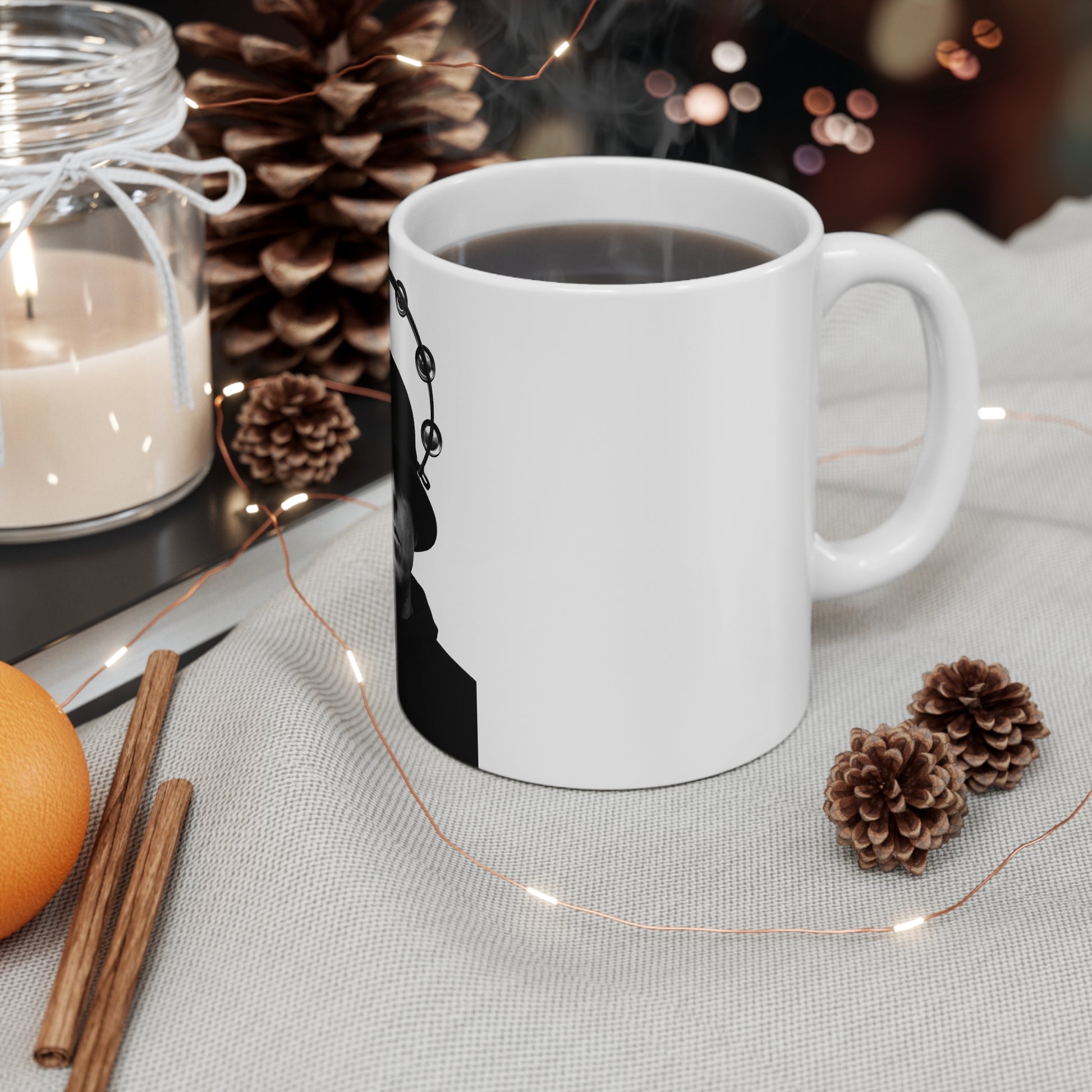 White coffee mug with black design, steaming hot black coffee, cozy setting with pinecones, cinnamon sticks, candle