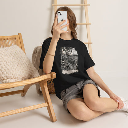 Woman sitting on the floor in black Oasis Importance of Being Idle tee, taking a mirror selfie