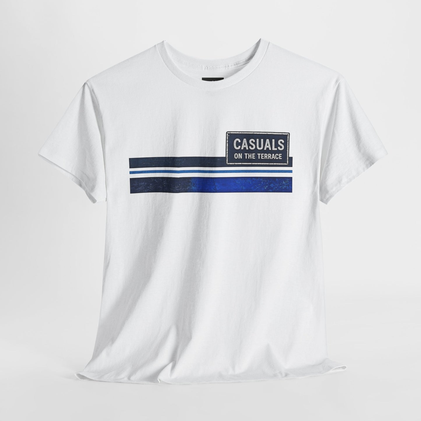 A white short-sleeve crewneck t-shirt with a graphic on the chest featuring a horizontal stripe design in navy blue, white, and dark gray, alongside a dark gray rectangular patch that reads 'CASUALS ON THE TERRACE'.