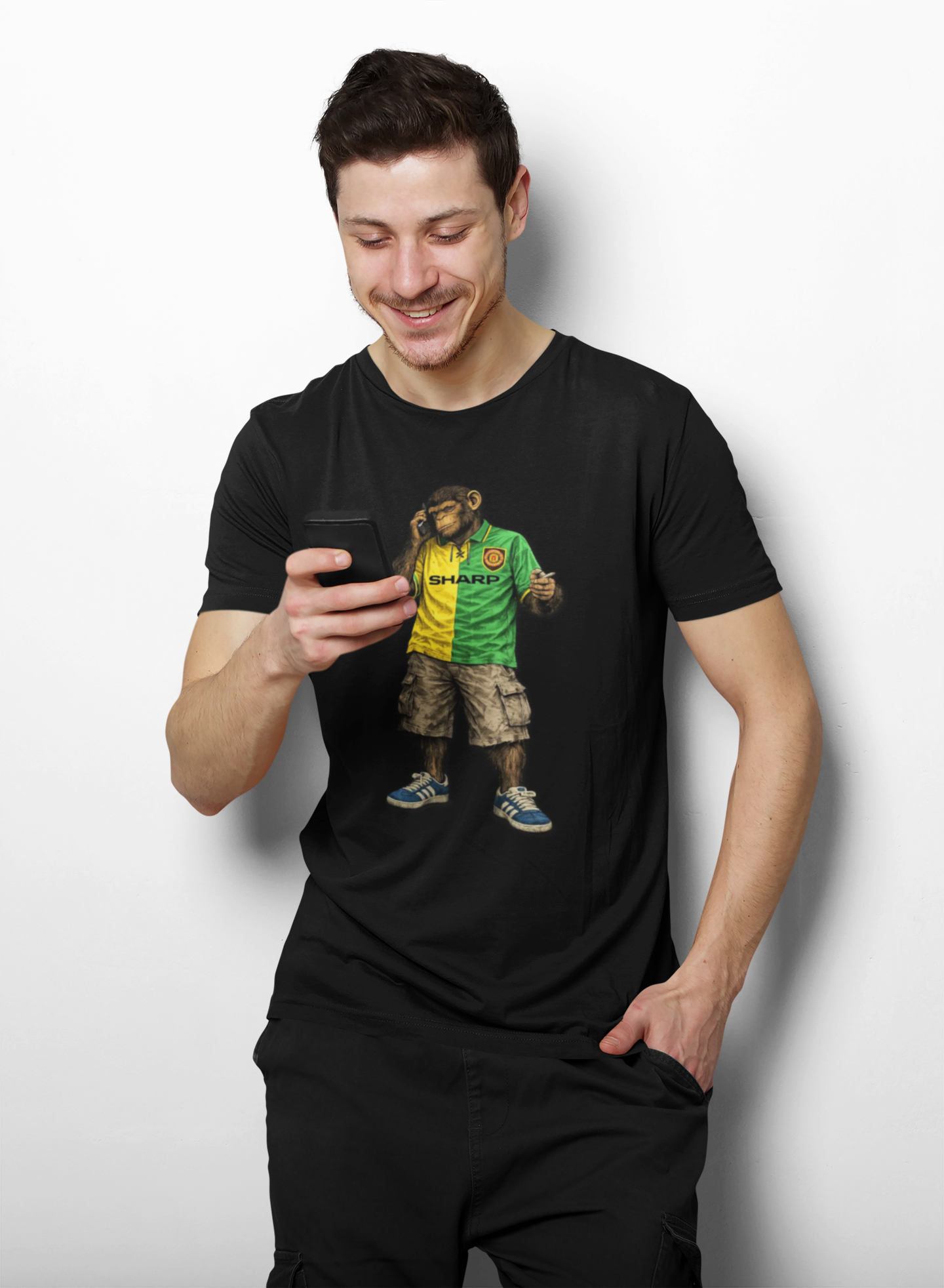 Man wearing a Black Man Utd Northern Monkeys t-shirt with a colorful graphic design, holding a phone.