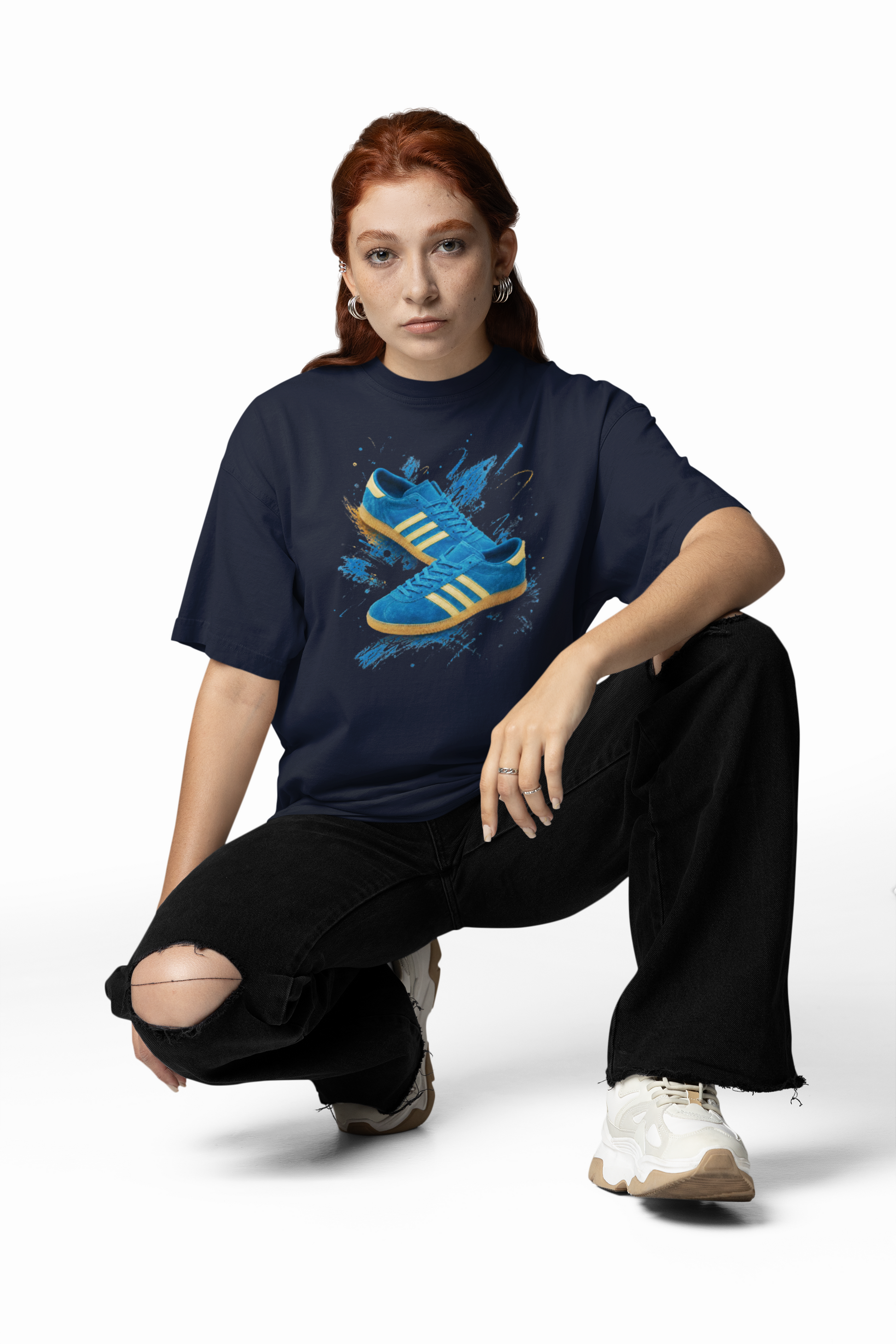 Navy blue t-shirt with a printed graphic of a blue suede trainer featuring cream stripes and a gum sole, surrounded by a blue and gold paint splatter design, with an "On The Terrace" logo on the neck label.