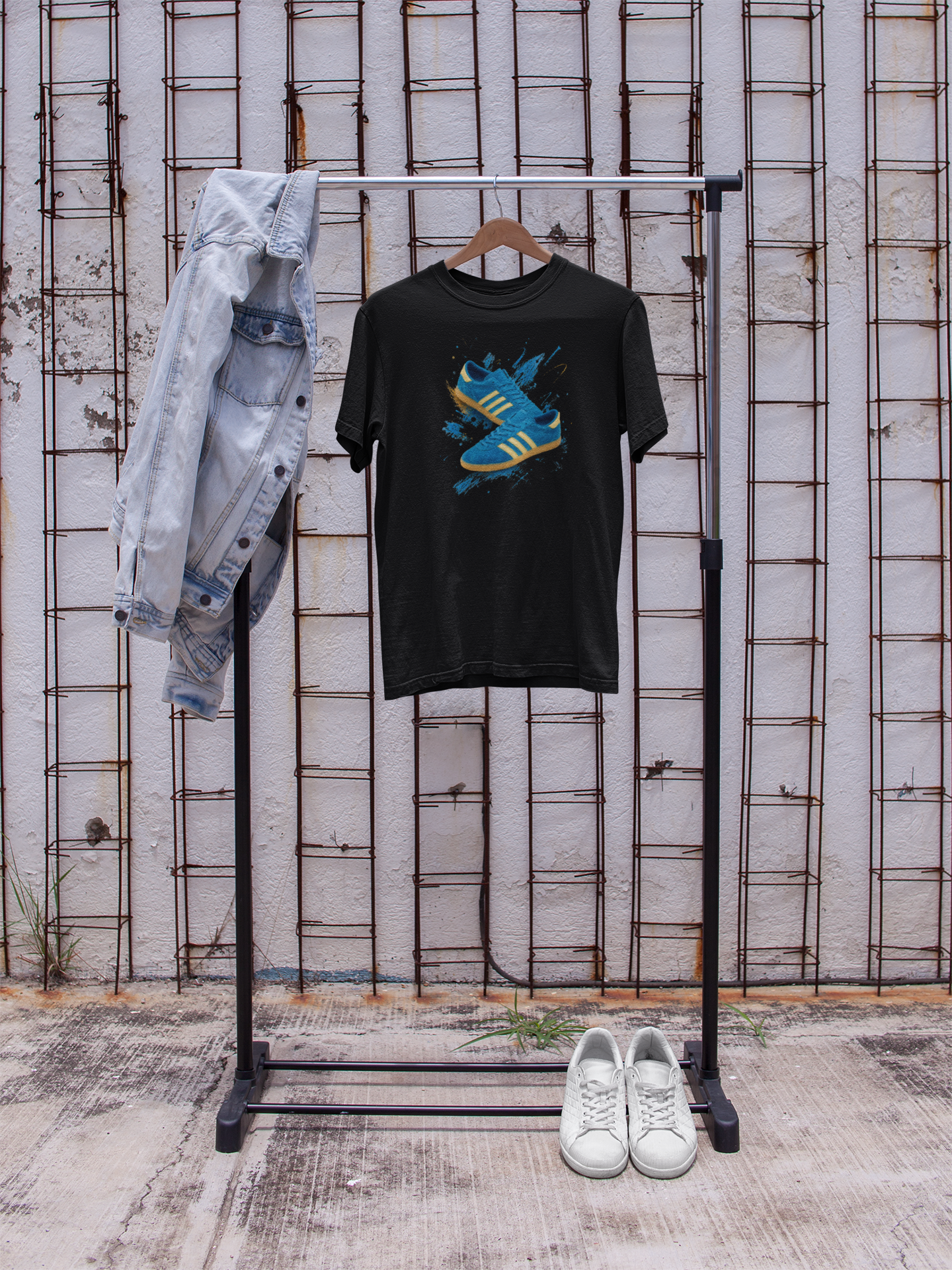 Black Gildan Softstyle t-shirt with a graphic print of a blue suede trainer with cream three stripes and gum sole, set against a blue and gold paint-splash background, On The Terrace neck label visible.