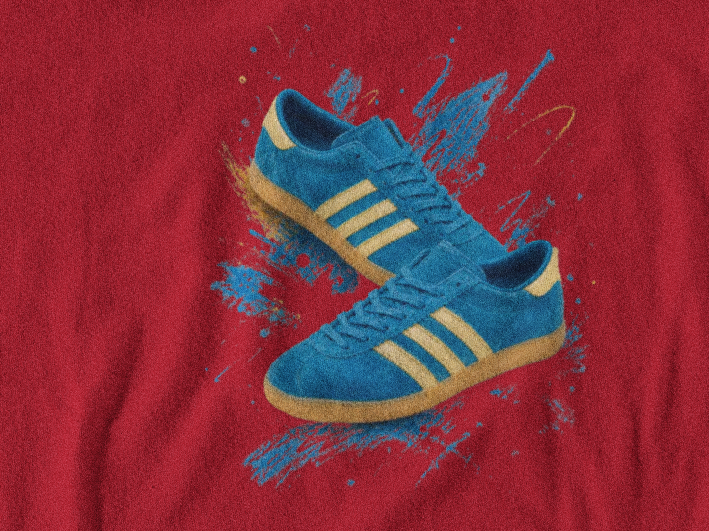 A pair of blue suede sneakers with yellow stripes and gum soles, printed on a red fabric background with blue paint splatters.