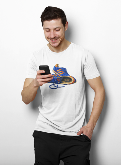 A man wearing a white t-shirt with illustration of blue and orange adidas Gazelle-style trainers, terrace casual sneaker graphic tee, vintage trainer collection, On The Terrace