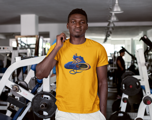 A man in a gym wearing a Gold t-shirt with hand-illustrated blue and orange retro terrace trainer sneaker graphic print, On The Terrace casual clothing brand
