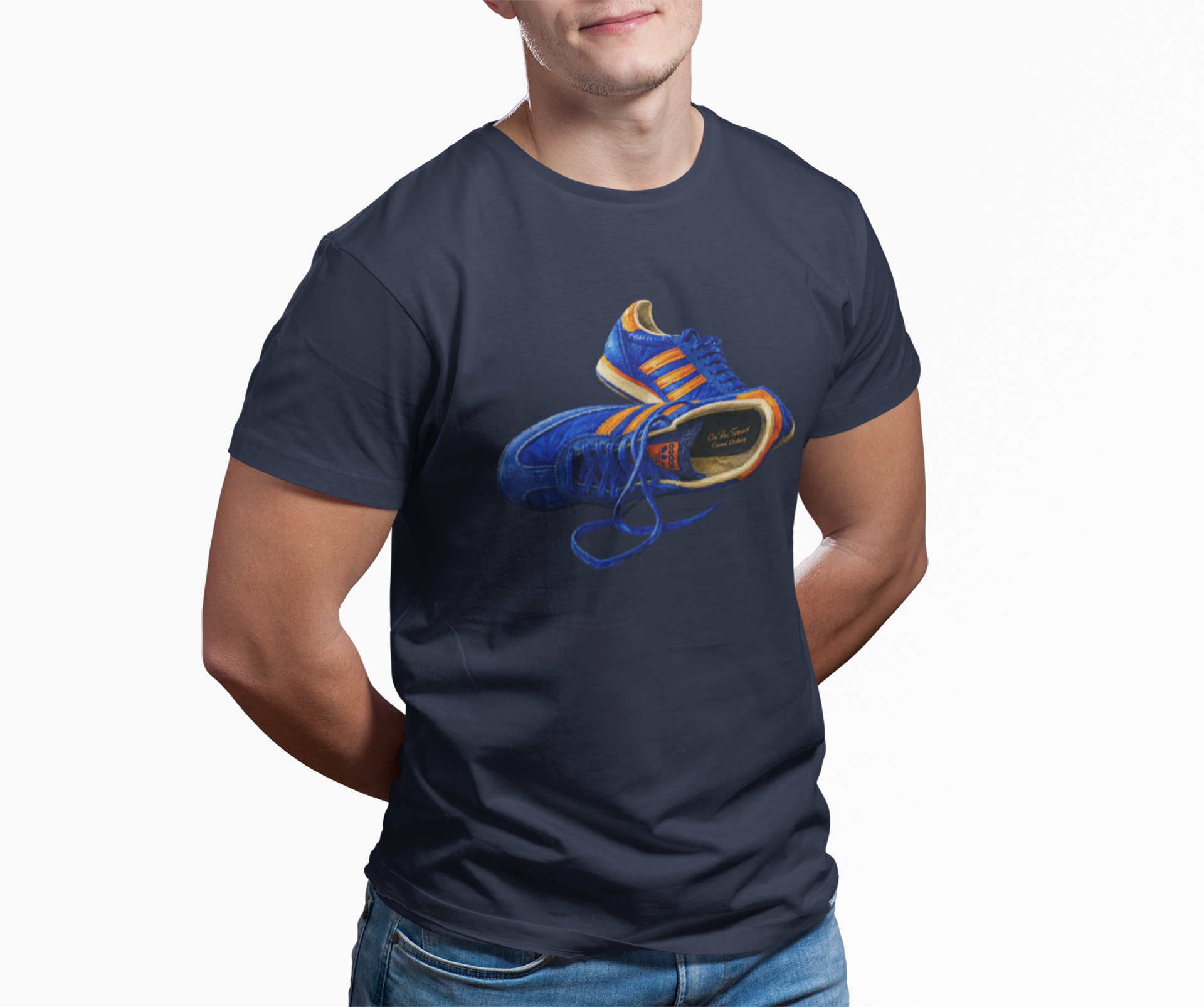 A man wearing a Navy t-shirt with hand-illustrated blue and orange retro terrace trainer sneaker graphic print, On The Terrace casual clothing brand

