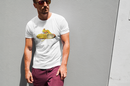 A man wearing a white crewneck t-shirt with a yellow sneaker graphic on the chest, paired with maroon pants, standing against a gray wall.