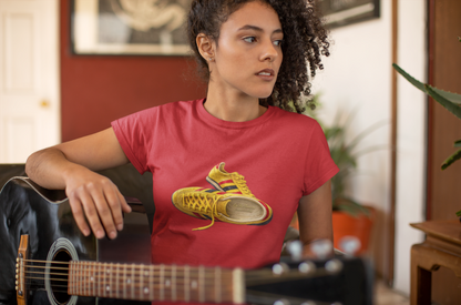 A woman with curly hair wearing a red t-shirt with hand-illustrated yellow, navy and red retro terrace trainer sneaker graphic print, On The Terrace casual clothing brand
