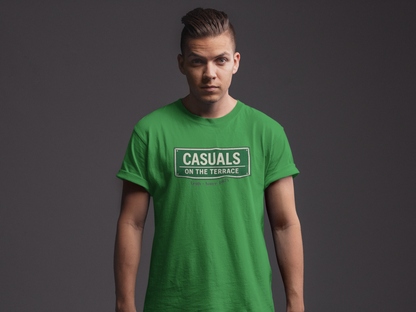 A man wearing a Hibernian green heavy cotton t-shirt flat lay featuring a central vintage green and white street sign graphic reading "CASUALS ON THE TERRACE" with "Leith • Since 1875" printed below, and an inner neck label for On The Terrace.