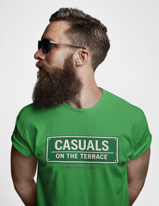 A man with a full beard and sunglasses wearing a Hibernian green heavy cotton t-shirt flat lay featuring a central vintage green and white street sign graphic reading "CASUALS ON THE TERRACE" with "Leith • Since 1875" printed below, and an inner neck label for On The Terrace.
