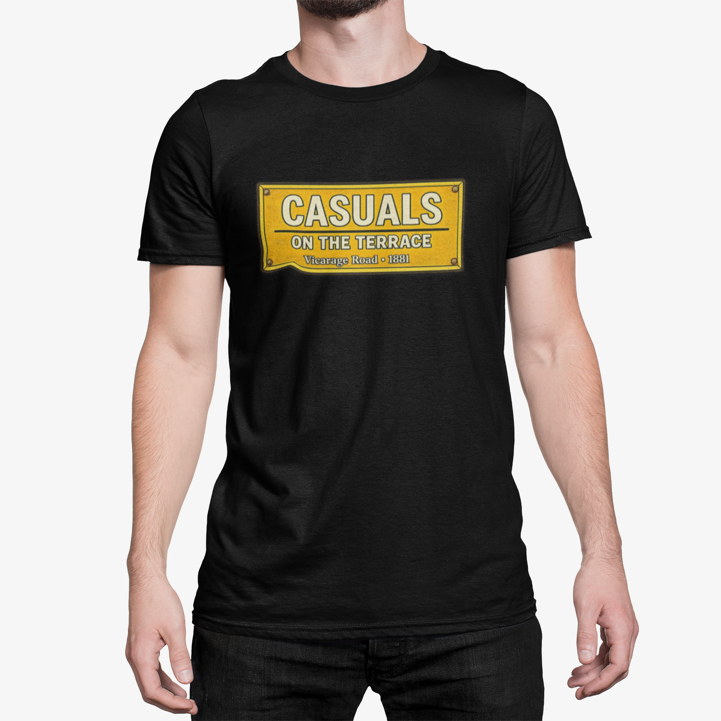 A man wearing a black short-sleeve Watford t-shirt with a yellow rectangular graphic on the chest that reads 'CASUALS ON THE TERRACE'.