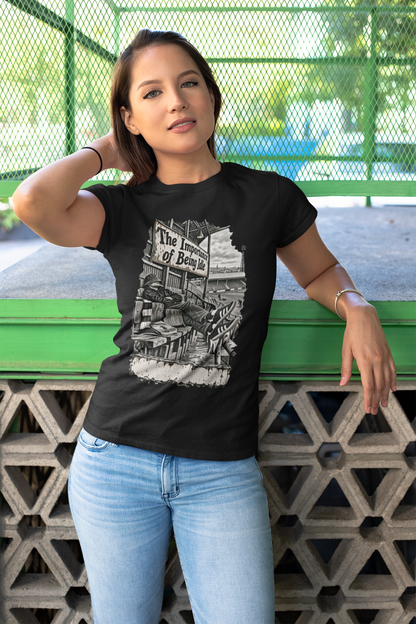 Woman in black Oasis Importance of Being Idle T-shirt and jeans against a green fence