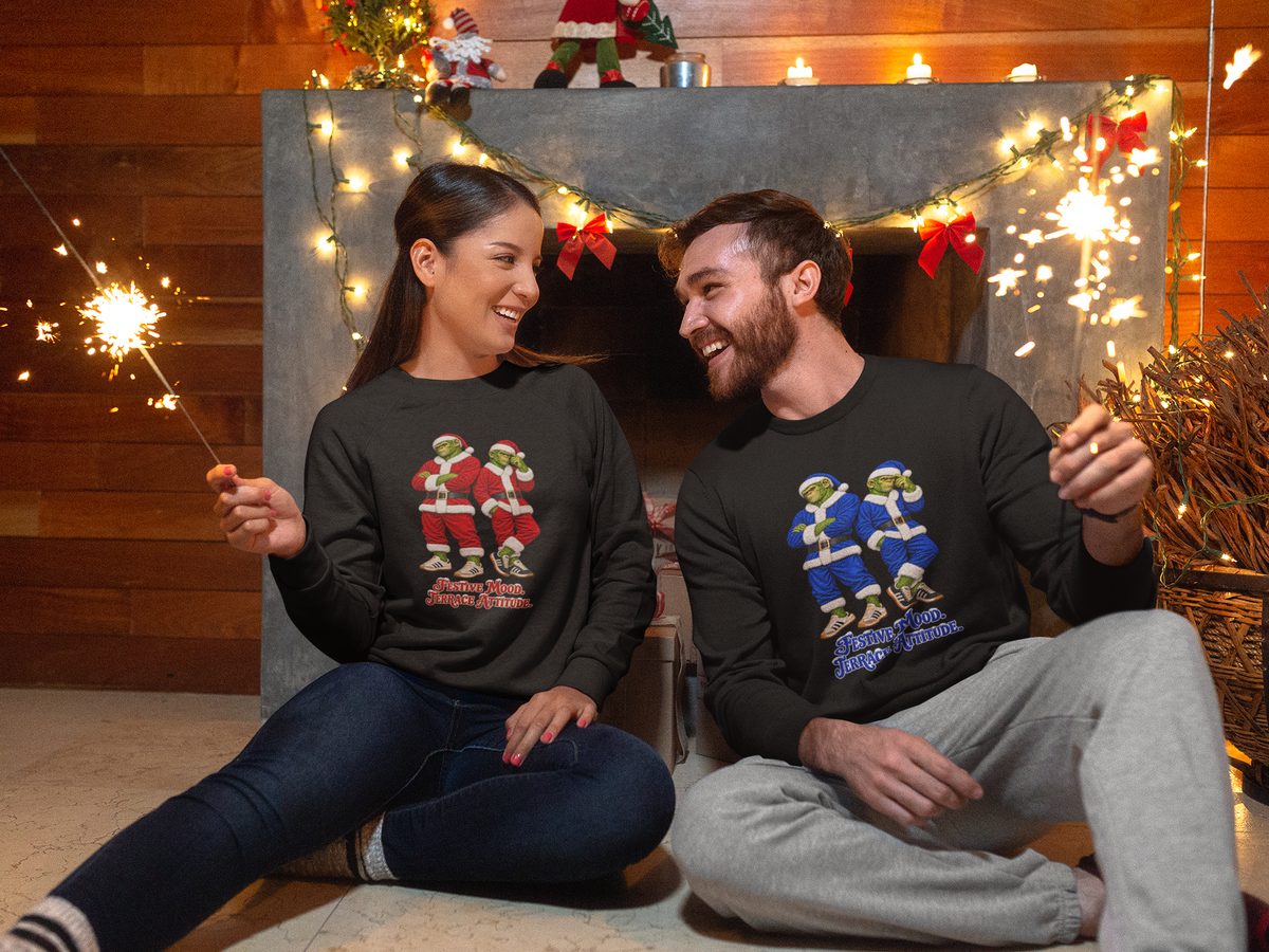 Couple sitting by Christmas lights wearing On The Terrace festive football sweatshirts
