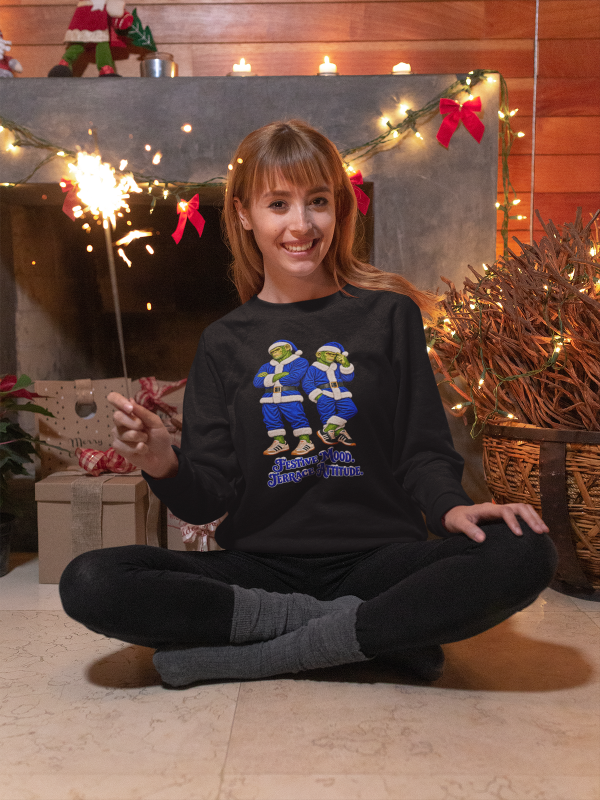 Woman sitting by Christmas lights wearing black blue-Santa Northern Monkeys sweatshirt