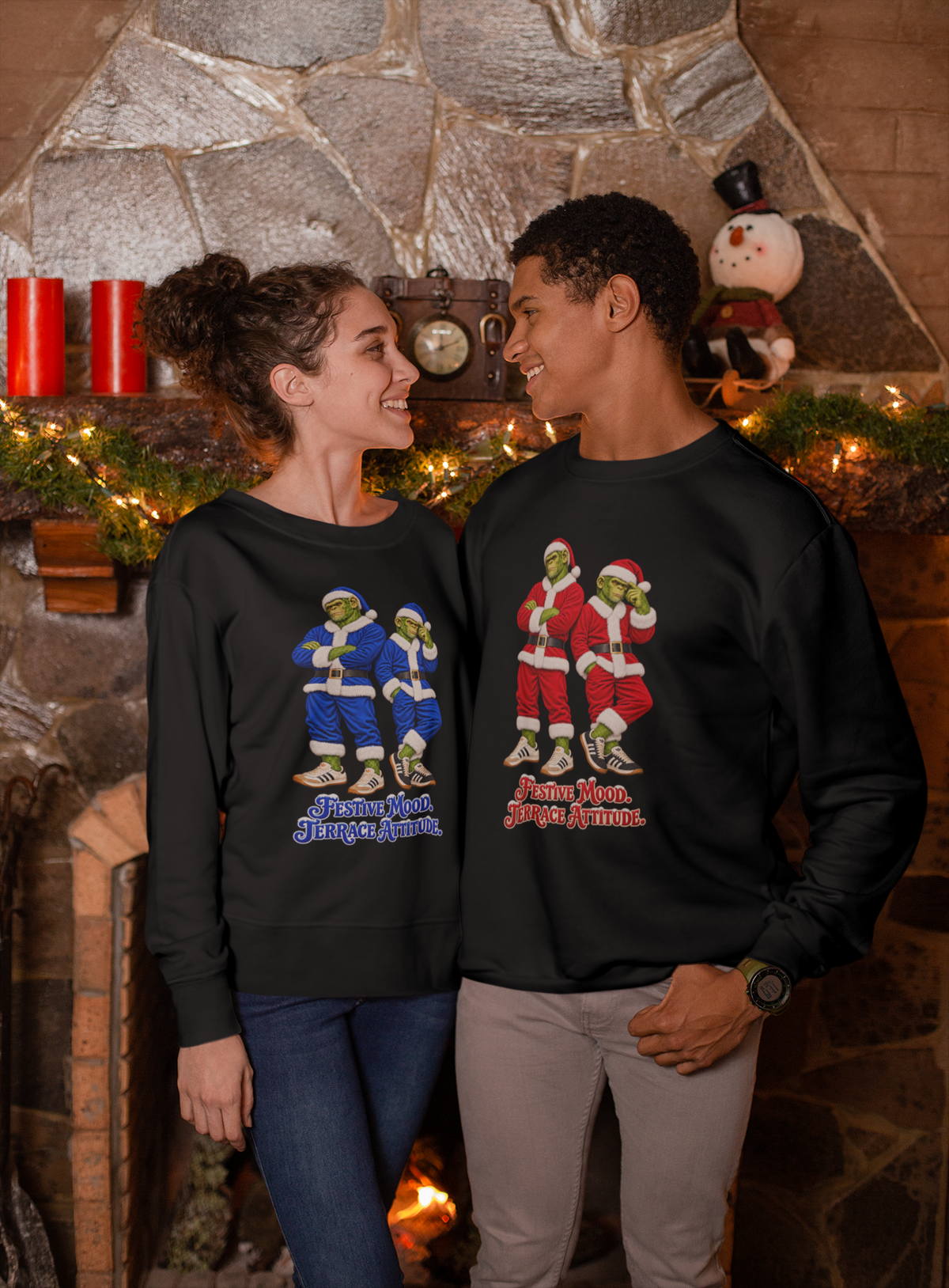 Two friends by a Christmas tree wearing the blue and red Northern Monkeys Santa jumpers