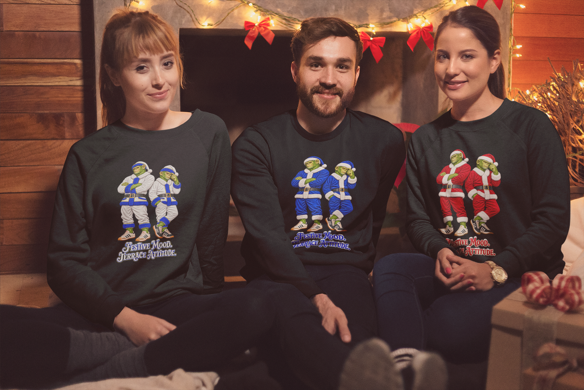 Three friends by Christmas lights wearing the white, blue and red Northern Monkeys Santa jumpers